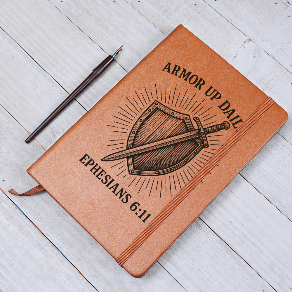 Brown leather prayer journal engraved with a shield and sword design and the words “Armor Up Daily – Ephesians 6:11.”